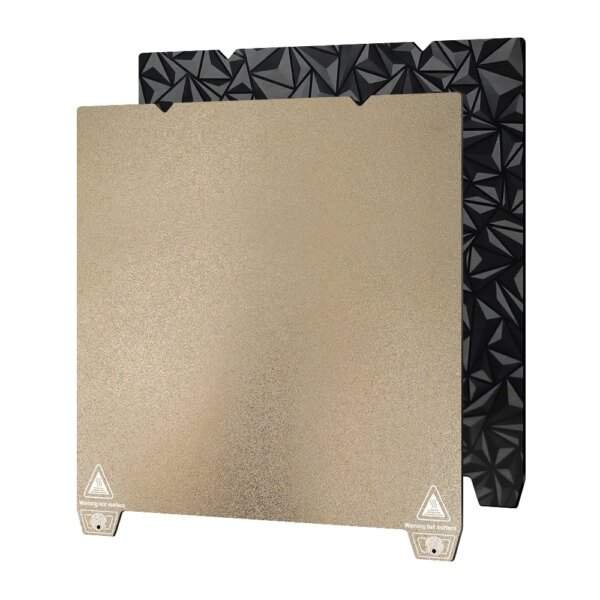 A metallic gold and black 3D printer build plate, featuring a smooth gold surface on one side and a textured, geometric black surface on the other.