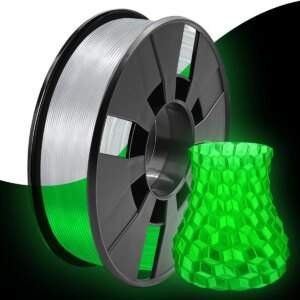 A black plastic spool of 3D printing filament, partially revealing a gradient of green and white material, next to a translucent green, hexagon-patterned 3D-printed object.